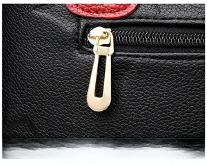Close-up of golden zipper puller on black lychee grain leather tote bag details