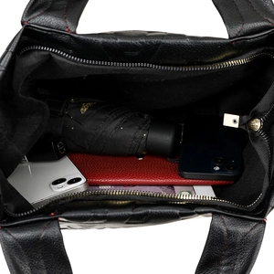 Large black leather tote bag with red stitching showing spacious interior and items