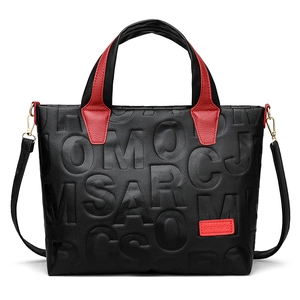 Black embossed leather tote bag with bold letters and contrasting red handles for women