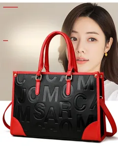 Détail du sac cabas en cuir noir avec anses rouges et lettrage en relief moderne