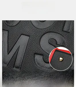 Vue détaillée du cuir noir à texture litchi avec bordure rouge et rivets dorés en métal