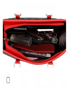 Vue intérieure du sac cabas en cuir noir montrant sa grande capacité et ses bords rouges