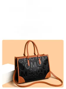 Détail du sac cabas en cuir grainé noir avec anses marron et lettrage en relief