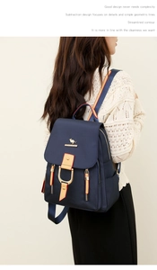 Détail d'un sac à dos bleu marine avec boucle fer à cheval dorée et poignée rayée