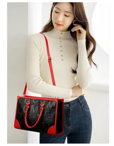 Détail du sac cabas rouge et noir avec lettres embossées et bandoulière sur modèle