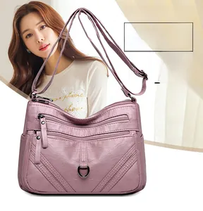 Detail of pink-purple crossbody bag showing multi-layered zipper pockets and pebble texture