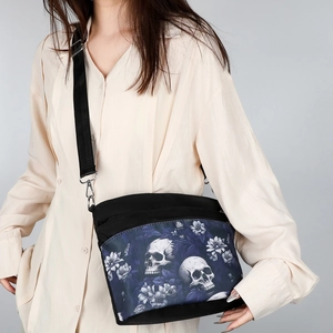 Schwarze Nylon-Umhängetasche mit Gothic-Totenkopf und blauem Blumenmuster am Modell