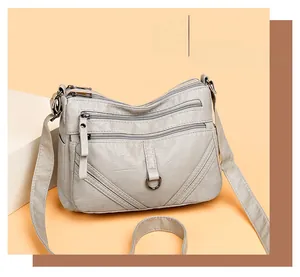 Detail of grey multi-layer crossbody bag showing silver zippers and soft leather texture