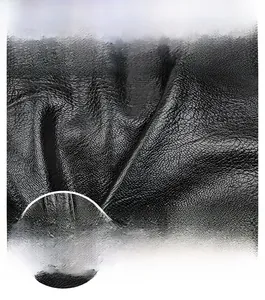 Detail of black pebbled leather texture and silver D-ring hardware on a shoulder bag