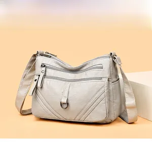 Detail of multi-layer zipper pockets on beige faux leather crossbody shoulder bag