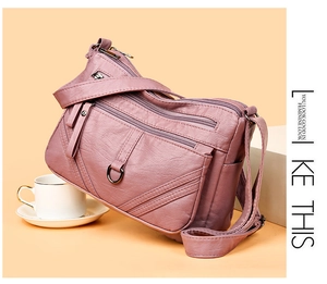 Detail of multi-layer dusty pink crossbody bag showing soft lychee texture and zippers
