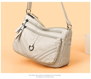 Detailed macro view of beige multi-zippered crossbody bag with vintage washed leather texture