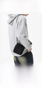 Detail of black nylon drawstring crossbody bag showing compact size on a model