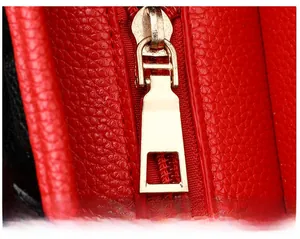 Détail d'une tirette de fermeture éclair dorée sur un sac cabas en cuir rouge