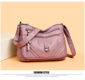 Close-up of pink crossbody bag featuring multi-layer zipper structure and pebbled leather texture