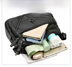 Detail showing high-capacity black crossbody bag with multiple zip compartments and essentials