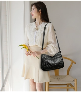 Detail of black soft leather crossbody bag with multiple zip pockets and metal hardware
