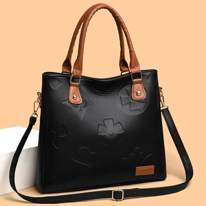Elegant black embossed leather tote bag with brown handles and adjustable shoulder strap