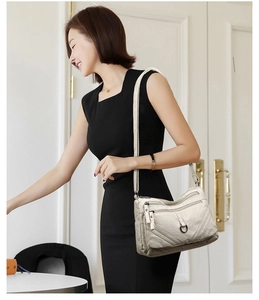 Side view of beige multi-pocket shoulder bag with metal ring detail on female model