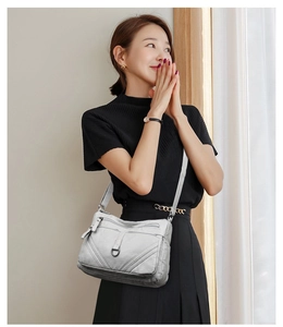 Close-up of women's grey crossbody bag with pebble leather texture and metallic details