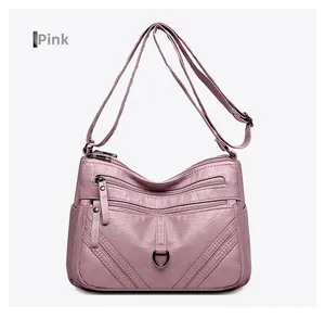 Detail of pink PU leather crossbody bag featuring multiple zipper pockets and metal ring