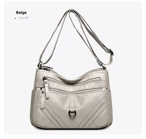 Detail view of beige multi-zippered crossbody bag with soft textured leather and metal D-rings