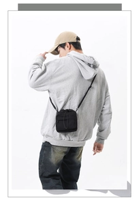Detail view of the black crossbody bag with drawstring closure and front zipper pocket