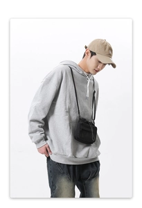 Detail of grey oversized hoodie styled with a crossbody phone bag and denim jeans