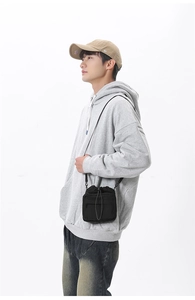 Close-up of black pleated drawstring mobile phone bag worn as a crossbody with nylon texture