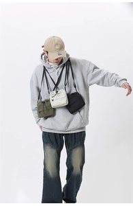 Three pleated drawstring crossbody bags in green, beige and black shown on a model