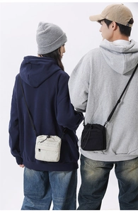 Detail of crossbody drawstring bags in cream and black on male and female models