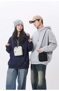 Detail of compact drawstring crossbody phone bag with front zipper pocket and strap