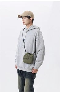 Olive green drawstring crossbody bag with front zipper shown on a model in daily wear