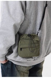 Detail view of the army green pleated drawstring crossbody bag worn by a model