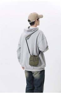 Detail of olive green nylon drawstring shoulder bag with front zipper pocket