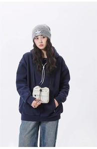 Detail view of a cream nylon drawstring crossbody bag paired with a navy blue hoodie