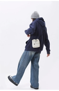 Detail view of beige drawstring nylon crossbody bag with adjustable black strap