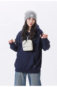 Detail of beige drawstring crossbody bag with front zipper pocket and canvas texture