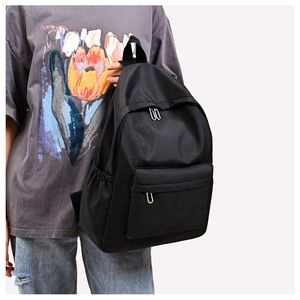 Detailed view of black nylon backpack featuring durable silver zippers and multi-pocket layout