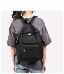 Minimalist black oxford backpack with front zipper pocket shown on a female model