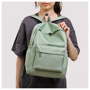Detail of light green oxford backpack featuring adjustable straps and side water bottle pocket
