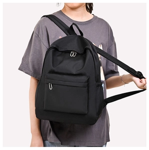Detail of black oxford fabric backpack showing side pocket and durable zipper closure