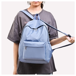 Close-up of light blue oxford backpack with zip front pocket and side water bottle holder
