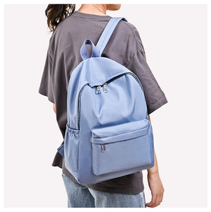 Detail of light blue waterproof nylon backpack showing front pocket and zip compartments