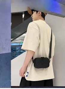 Fashionable men's black hard shell crossbody bag featuring a textured finish and strap
