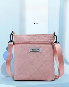 Détail d'un sac bandoulière matelassé rose avec fermeture éclair et étiquette tissée