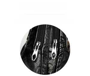 Detail of dual silver geometric metal zippers on black pleated PU leather texture