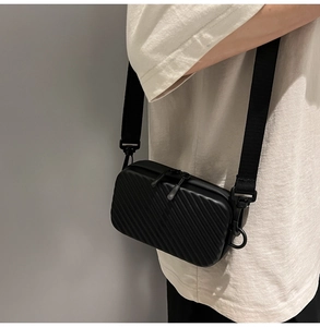 Detail of black hard shell crossbody bag featuring anti-slip texture and dual zippers