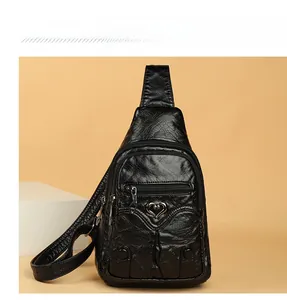 Detail of black faux leather sling bag with heart buckle and three zipper layers