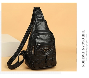 Detail view of black vintage PU leather chest bag with heart charm and multi-zipper texture
